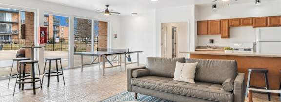 A room with a pool table, bar stools, and a fan.