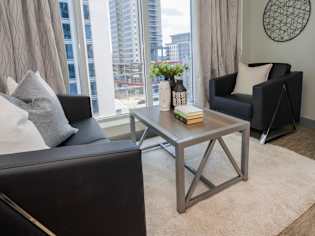 A living room with a black couch, a grey coffee table, and a round decorative item on the wall.
