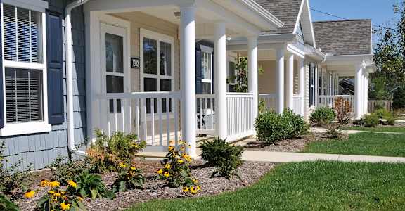 A house with a white porch and a green lawn.