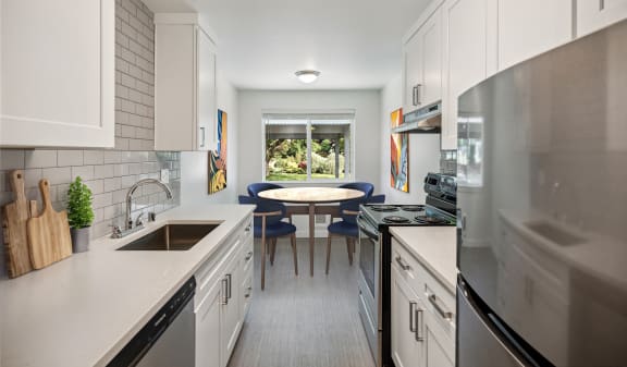 a kitchen with white cabinets and stainless steel appliances and a table with blue chairs