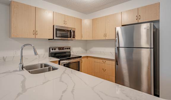 A kitchen with a sink, stove, and refrigerator.