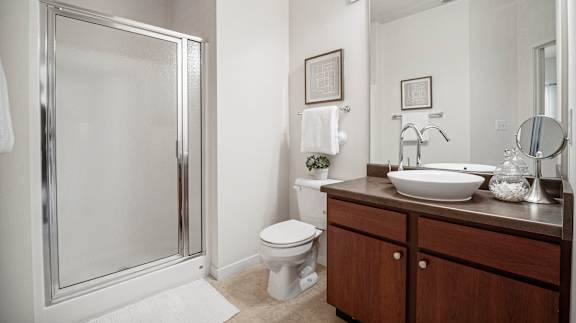 A bathroom with a toilet, sink, mirror, and shower.