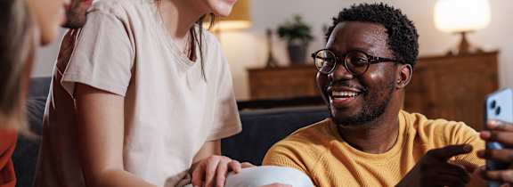 A couple is lying on a bed with pillows and a laptop.
