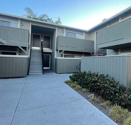 A concrete building with a grey facade and a small garden in front.