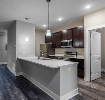 an empty living room with a kitchen and a door to a balcony