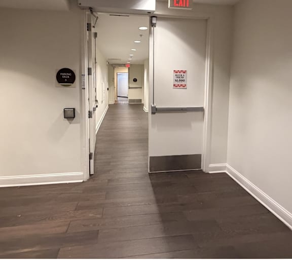 A long hallway with a red exit sign on the ceiling.