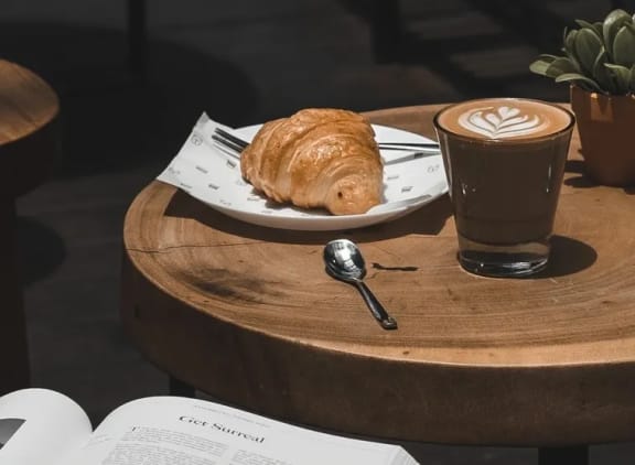 a pastry and coffee on a table with an open book