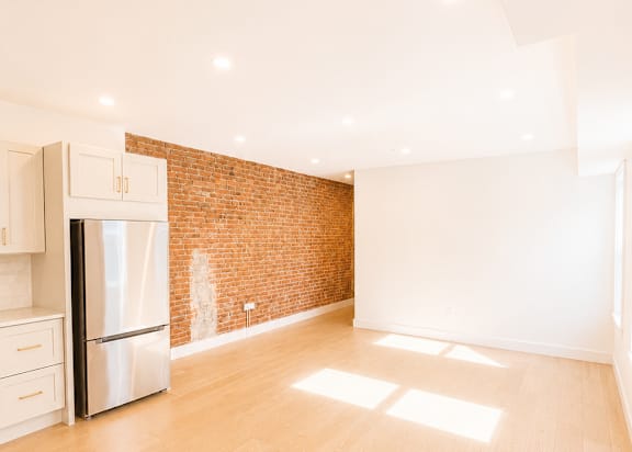 A kitchen with a refrigerator and wooden floors.