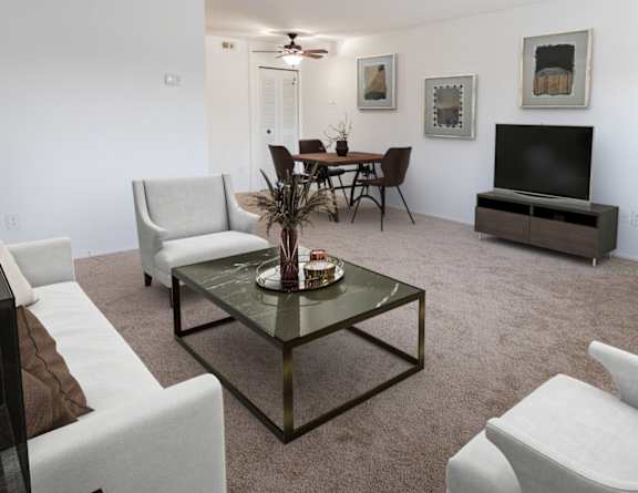 A living room with a glass coffee table and white chairs.