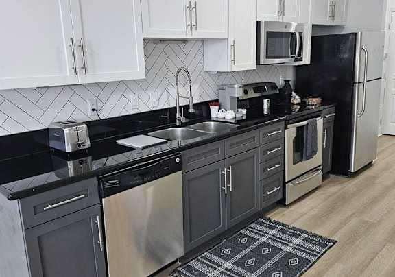 a black and white kitchen with stainless steel appliances and white cabinets