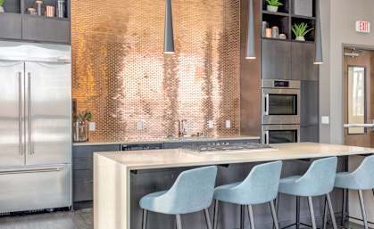 a kitchen with stainless steel appliances and a bar with blue chairs