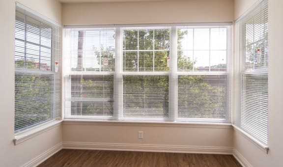 a large window with mini blinds in a room with wooden floors at Crawford Square Apartments & Townhomes