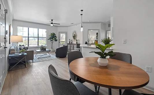 A dining room with a round wooden table surrounded by grey chairs.