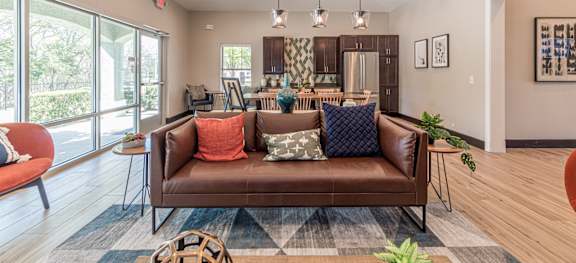 A living room with a brown couch and a rug.