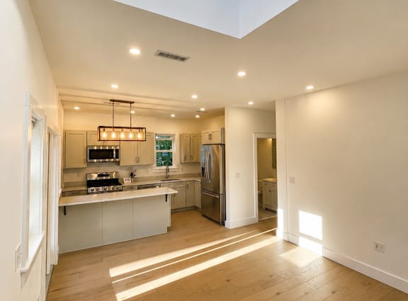 A kitchen with a skylight and wooden floors.