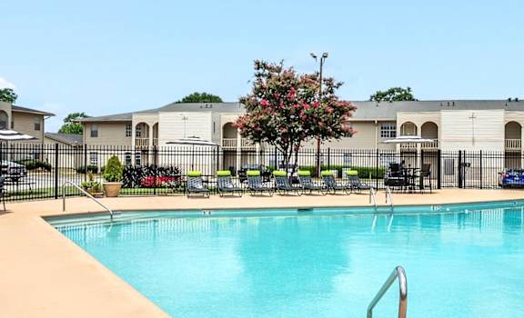 A swimming pool in front of a building with a tree in the background.