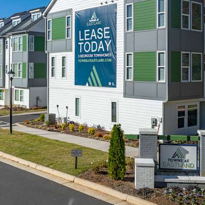 A white building with a green sign that says "Lease Today".