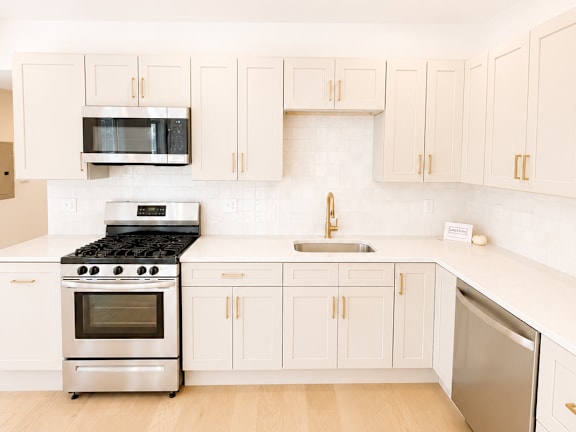 A kitchen with white cabinets and appliances.