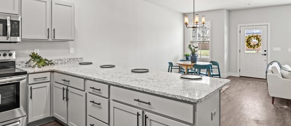 an open kitchen and living room with white cabinets and stainless steel appliances
