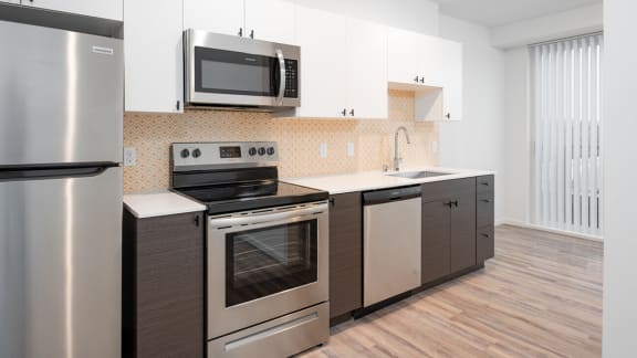 a kitchen with stainless steel appliances and white cabinets at The Loop at Green Lake, Seattle, 98115