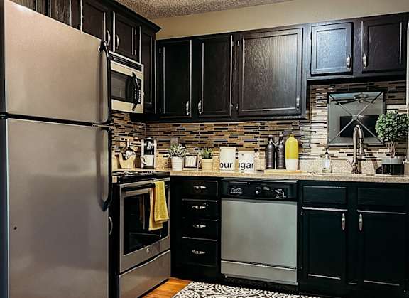 A kitchen with a refrigerator, oven, and microwave.