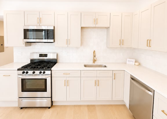 A kitchen with white cabinets and appliances.