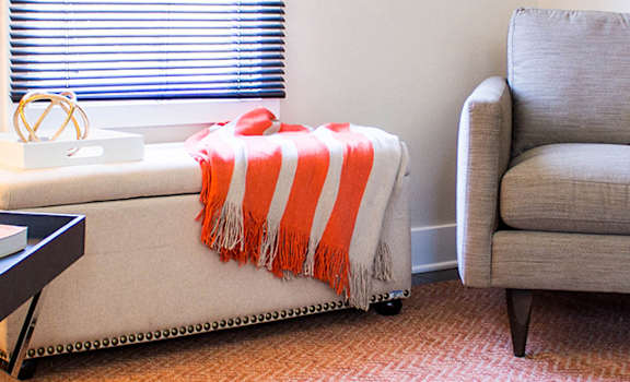 A living room with a grey couch, a coffee table, and a lamp.
