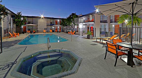 A swimming pool area with orange chairs and a table.