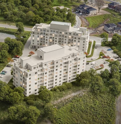 A large white building sits in the middle of a green area with a river running along the bottom.