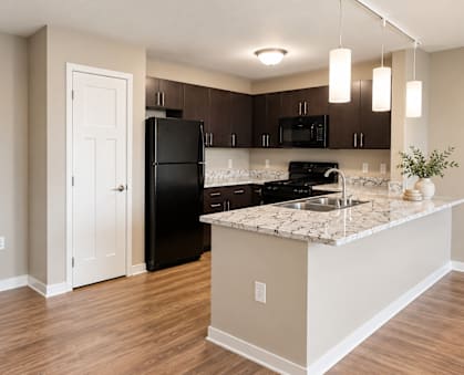 A kitchen with a black refrigerator and a marble countertop.