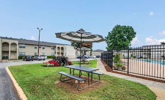 A picnic table is surrounded by a black fence and a pool.