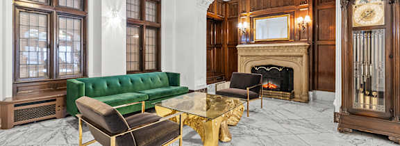 A living room with a green couch, a fireplace, and a large mirror. at The Exeter Apartments, Seattle, Washington