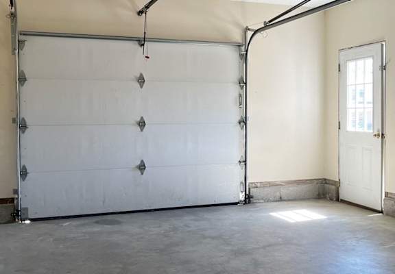 A garage with a white door and a white wall.