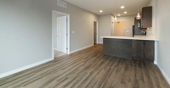 A room with a wooden floor and a bar area.