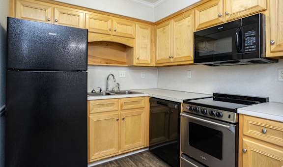 an empty kitchen with wooden cabinets and black appliances
