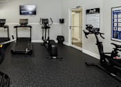 Thumbnail 26 of 32 - A gym room with exercise equipment and a television.