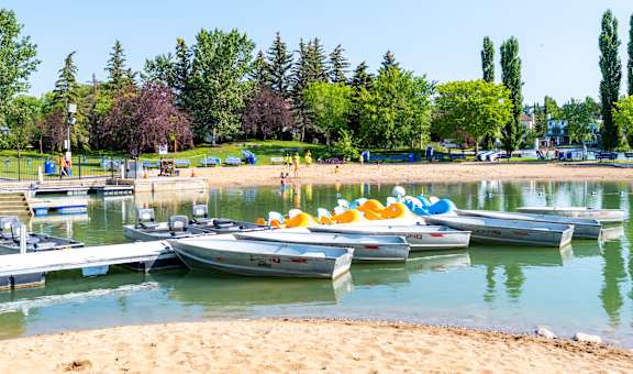 A group of boats are docked at a pier on a sunny day  at Vibe Apartments at Arbour Lake in Calgary, AB