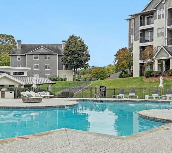 A swimming pool in front of a building with a fence around it.