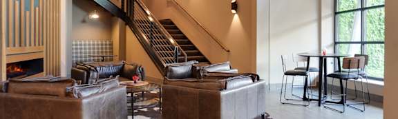 A living room with a couch, chairs, and a staircase.