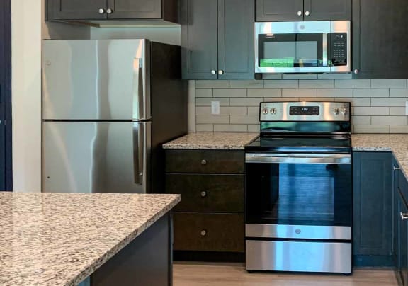 a kitchen with stainless steel appliances and dark cabinets