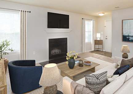 Bright living room with fireplace, wall-mounted TV, and large windows in The Charleston floor plan at Palmetto Place Apartments
