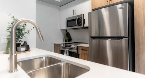 A modern kitchen with a stainless steel refrigerator and a white sink.