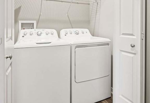 Laundry closet with side-by-side washer and dryer hookups, overhead wire shelving, and convenient storage space.