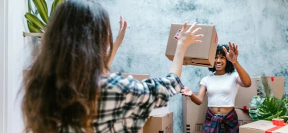 two women playing with boxes in a room with moving boxes