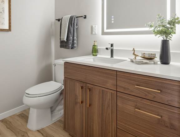 A bathroom with a toilet, sink, and mirror.