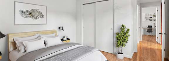 A bedroom with a large bed and a plant in a white pot.
