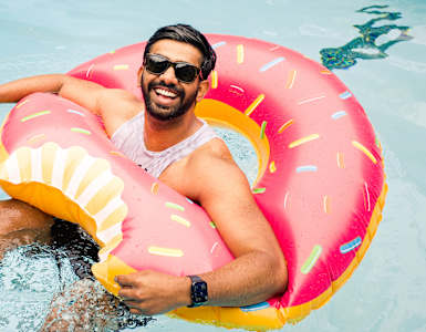 a man swimming in a pool with an inflatable donut ring in the water