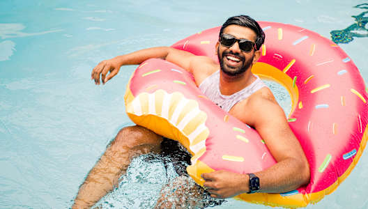 a man swimming in a pool with an inflatable donut ring in the water
