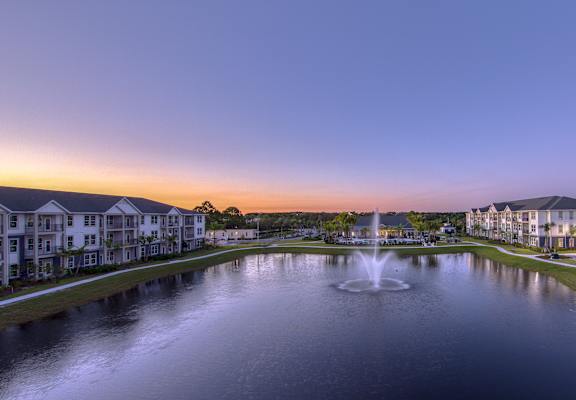 a fountain in the middle of a pond with houses around it