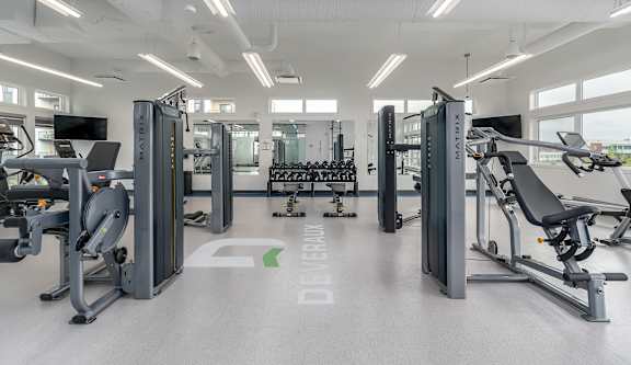 A gym with a variety of equipment including treadmills, weights, and exercise machines.